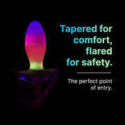 White tapered butt plug with a flared base, glowing vibrant LED colors of purple, pink, and green.