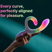 Hand holding a white Illumination Rabbit LED vibrator with rainbow color-changing light effects.