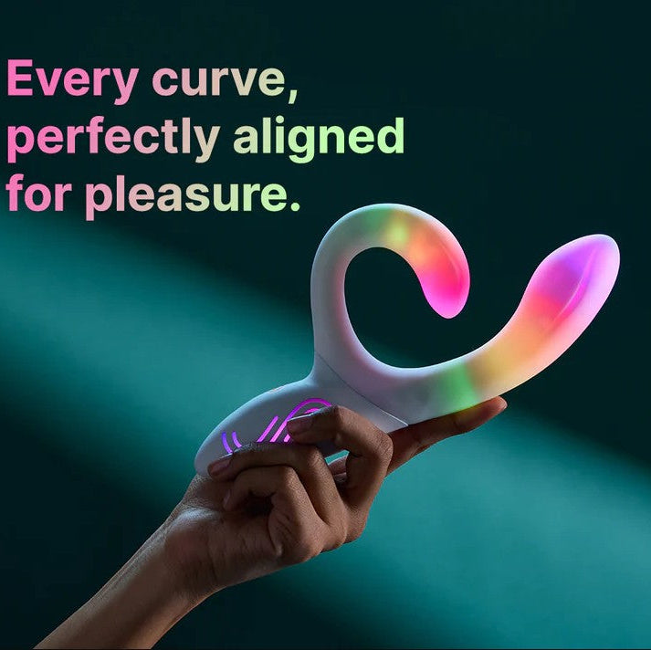 Hand holding a white Illumination Rabbit LED vibrator with rainbow color-changing light effects.