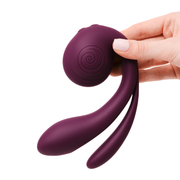 Hand holding a purple silicone SVibe Gizi Pro triple stimulator with curved arms and a clitoral bulb.