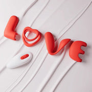 Red silicone couples vibrator set spelling "LOVE" with a white wireless remote.