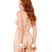 A woman with long red hair, dressed in pink lingerie, stands with her back to the camera. Her hands are cuffed behind her using Peaches 'n Cream Fur Handcuffs. The background is plain white.