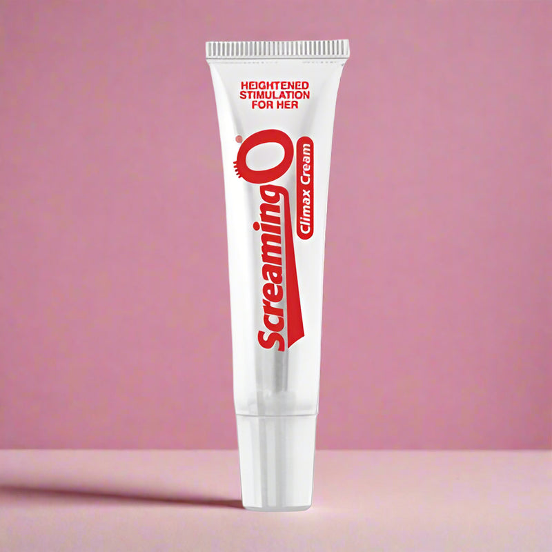 A white tube labeled "Screaming O Clitoral Climax Cream" stands upright against a pink background, with packaging that advertises “heightened stimulation for her” in red text near the top.