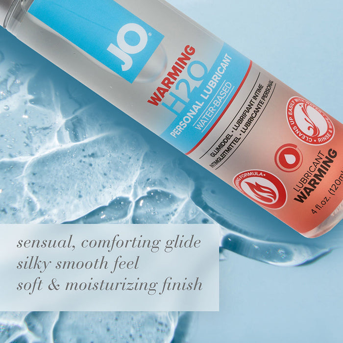 A bottle of Jo H2O Warming Water Based Lubricant rests on a surface with some spilled liquid. Beside it, text reads: "sensual, comforting glide, silky smooth feel, soft & moisturizing finish.
