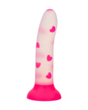 A Glow Stick Heart Silicone First Time Glow in the Dark Dildo from CalExotics, with a conical shape, featuring a gradient from translucent to pink at the base, decorated with a pattern of pink hearts all over.