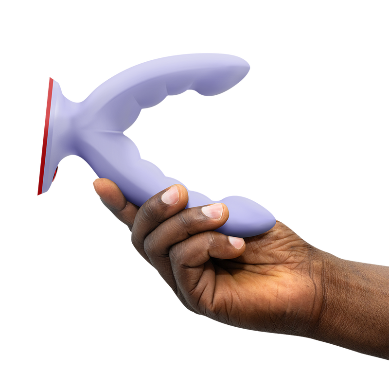 Hand holding a lavender silicone grinding dildo with a curved, ridged design and red suction base.