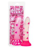 A pink, glow-in-the-dark silicone dildo called "Glow Stick Heart Silicone First Time Glow in the Dark Dildo" with heart shapes, displayed in its packaging, which includes details like "suction cup base," "harness compatible," and.