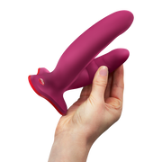 Hand holding a magenta silicone Fun Factory Ryde grinding dildo with a red suction base.