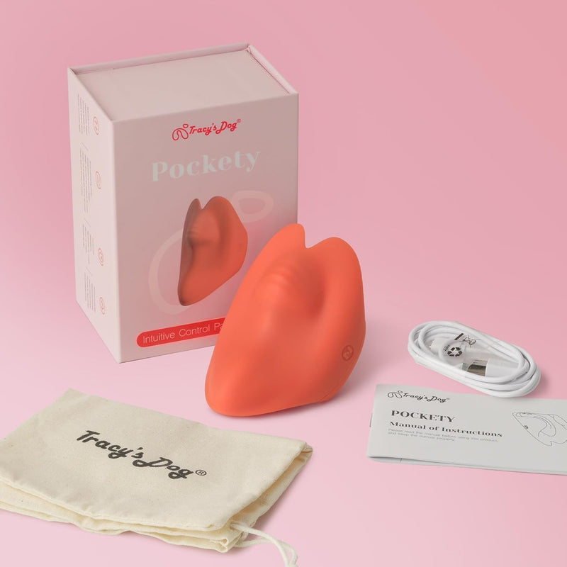 Tracy's Dog Pockety palm vibrator in coral, with its box, white USB cable, manual, and canvas pouch.