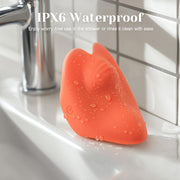 Orange silicone Pockety palm vibrator with water droplets on a white bathroom sink.