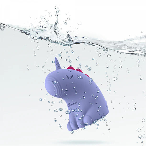 The Dreamy Pulse – The Magical Unicorn Pulse Vibrator, featuring closed eyes, a red mane, and body-safe silicone in purple, is shown underwater surrounded by bubbles and splashes.