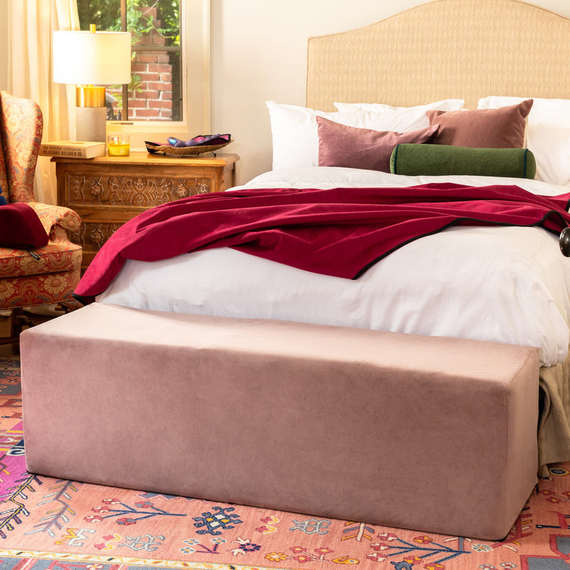 Pink microvelvet Liberator Aria convertible sex chair and bench at the foot of a bed.