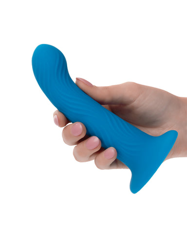 A person's hand with pink manicured nails holding a blue, dolphin-shaped, powerful suction cup CalExotics Wave Rider Ripple First Time G-Spot and Prostate Silicone Dildo against a white background.