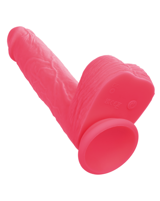 A CalExotics Silicone Stud Rumbling & Thrusting 9.5 Inch Pink Dildo with detailed textures and a suction cup base is placed against a plain white background. Made from silky silicone and featuring a realistic design, the item’s suction base allows for hands-free use on smooth surfaces.
