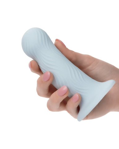A hand with pink nail polish holding a CalExotics Wave Rider Foam Short, Girthy 4.75 Inch Liquid Silicone Dildo against a white background.