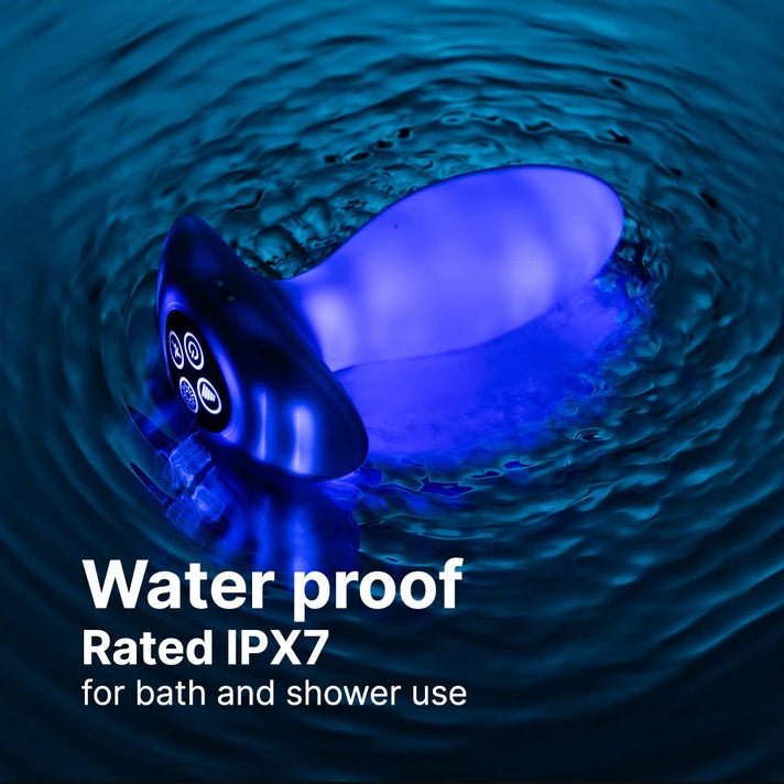 White, waterproof butt plug with a flared base, glowing blue in rippling dark water.