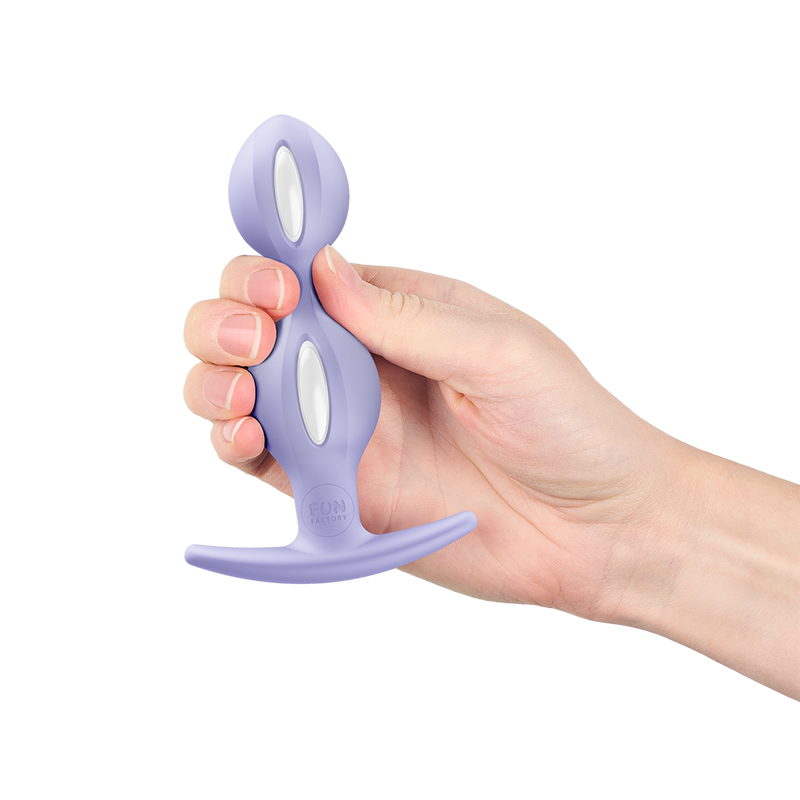 Hand holding a lavender silicone butt plug with a tapered tip, flared base, and two white oval inserts.