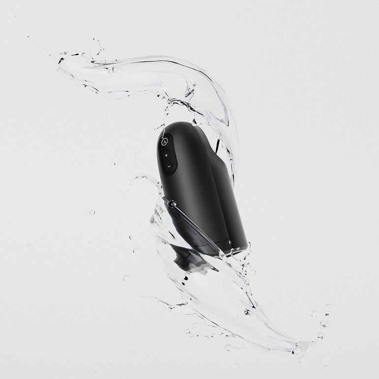 The Arcwave Ion 2 Penis Masturbator with Pleasure Air Suction, shown in sleek black amid splashing water on a light gray background, highlights its water-resistant design and innovative Pleasure Air technology.