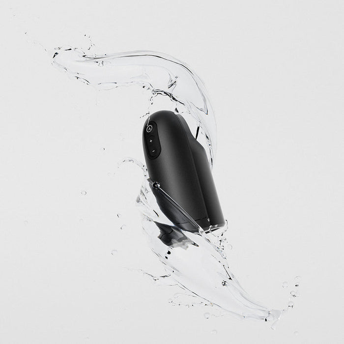 The Arcwave Ion 2 Penis Masturbator with Pleasure Air Suction, shown in sleek black amid splashing water on a light gray background, highlights its water-resistant design and innovative Pleasure Air technology.