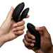 Two hands hold the black We-Vibe Chorus Pro Wearable Couples' Vibrator with triple motors and its buttoned remote against a white background.