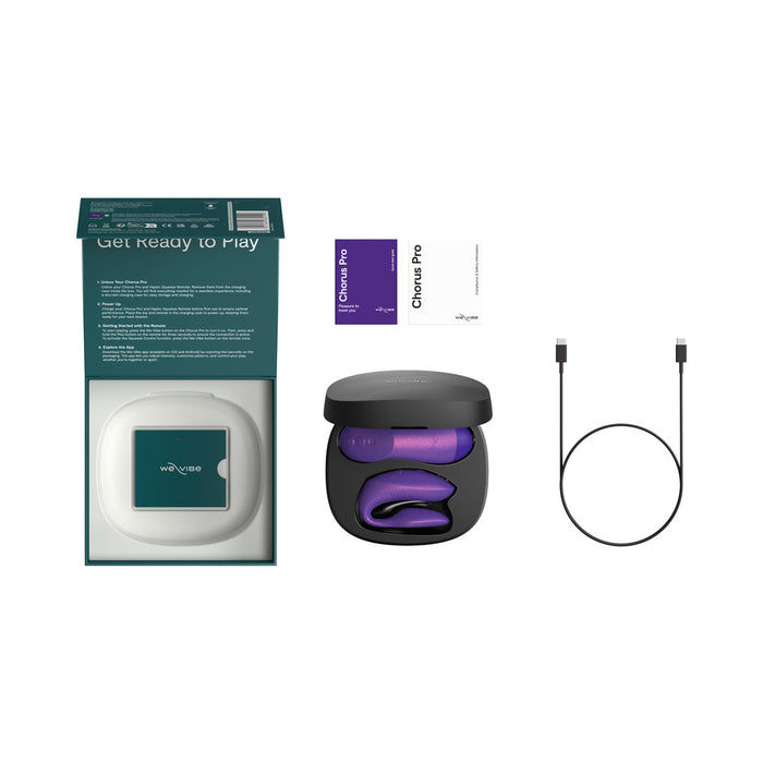 An open box with a teal interior displays the We-Vibe Chorus Pro Wearable Couples’ Vibrator with Triple Motors & Remote in a black charging case, two instruction booklets, and a black USB charging cable on a white background.