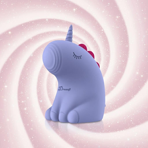 The Dreamy Pulse – The Magical Unicorn Pulse Vibrator, a cute body-safe silicone figurine in purple with closed eyes, a horn, and red mane accents, is set against a pink and white swirled background.
