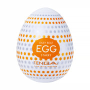 A white Tenga Egg with orange and gray star patterns, labeled "EASY BEAT EGG STARRY" and "TENGA LIVE WITH WONDER," is part of the Tenga Egg Standard 3 Pack Disposable Masturbators I and features a textured sleeve for enhanced sensation.