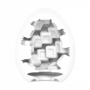 A white Tenga Egg Standard 3 Pack Disposable Masturbators I is shown with a cutout displaying an intricate, textured sleeve of interlocking geometric shapes and squares that create a complex, three-dimensional interior pattern.