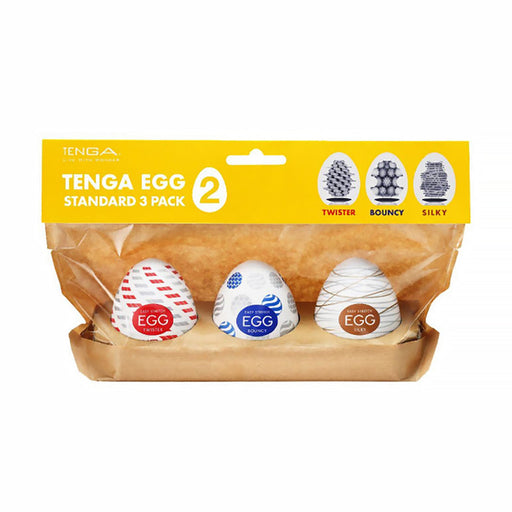 The Tenga Egg Standard 3 Pack Disposable Masturbators II includes three white egg-shaped pocket strokers with red, blue, and gold designs labeled "Twister," "Bouncy," and "Silky" on a yellow and brown holder.
