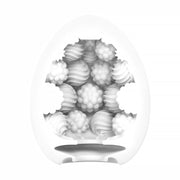 The Tenga Egg Standard 3 Pack Disposable Masturbators II features white, egg-shaped sleeves with open sections, revealing textured interiors in whip and berry patterns. The product is shown against a plain white background.