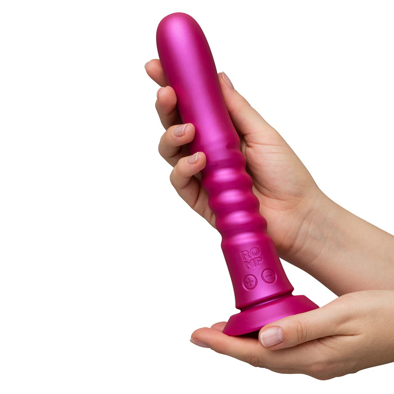 Pink ROMP Jiggle thrusting vibrator with a ribbed body, control buttons, and suction base, held by two hands.