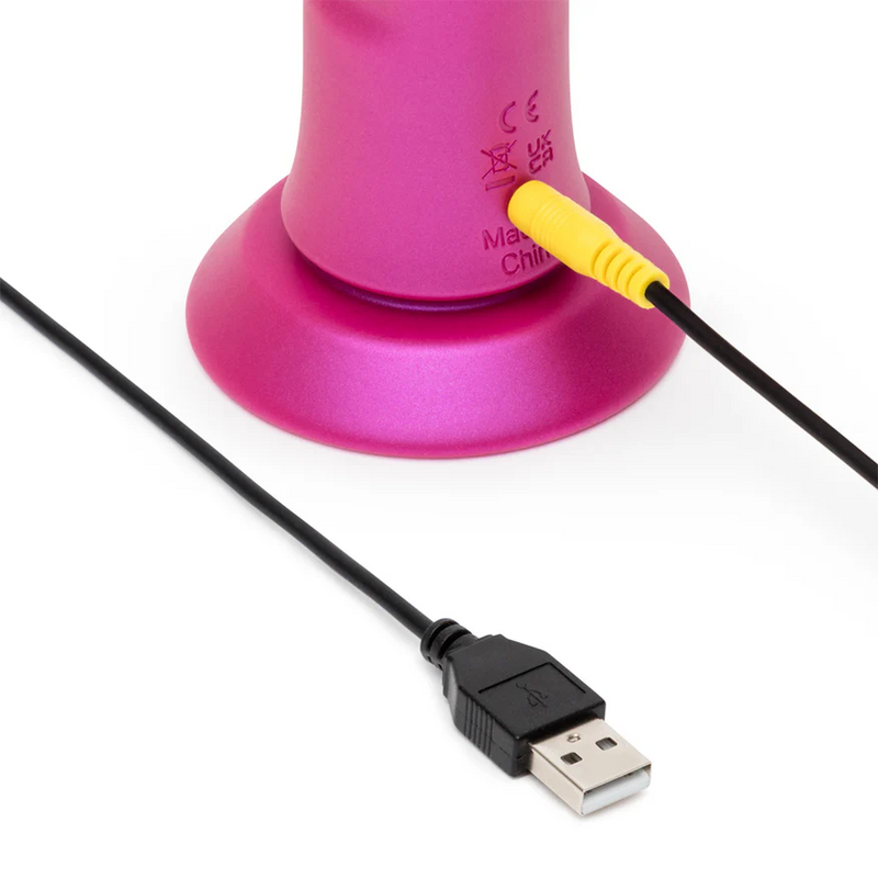 Pink ROMP Jiggle vibrator base with yellow charging port and black USB cable on a white background.