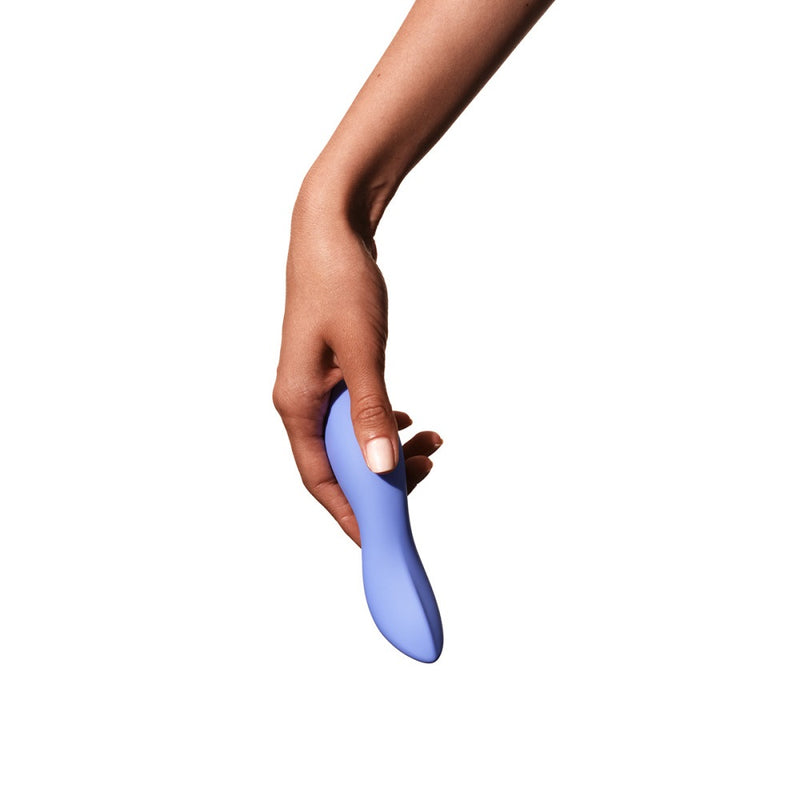 A hand with light brown skin and manicured nails holds the Dame Dip Beginner's Internal & External Silicone Vibrator in Periwinkle against a plain white background.