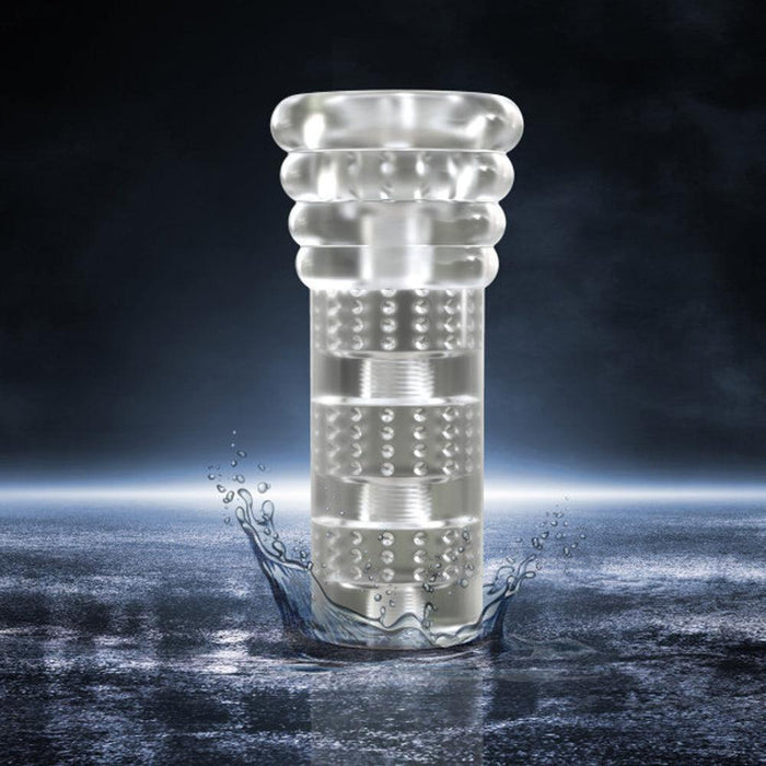 The Blush All Nighter Glow in the Dark Textured Clear Self Lubricating Stroker, a transparent cylindrical object with textured rings and a patterned surface, stands upright in the middle of a water surface, causing a splash. The dark and mysterious background, adorned with subtle light reflections, creates a dramatic effect.