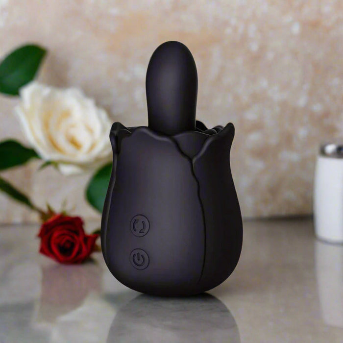 The Bums and Roses Powerful Rimming Tongue Vibrator in black by Creative Conceptions is designed with a petal motif at the base and a smooth, rounded tip. Made from body-safe silicone, it includes two control buttons near the bottom for adjusting settings and power.