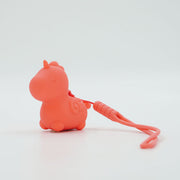 The Unihorn Mini - Peachy Pony Discreet Vibrator is a small, coral-pink, body-safe silicone unicorn with a closed-eye expression and curly tail, attached to a matching lanyard on a plain white background.