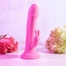 The Somebunny to Love Uncut Look Rabbit Vibrator, featuring a phallic shape and rabbit-shaped clitoral stimulator, stands upright among pink roses on the left and light hydrangeas on the right.