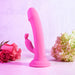 The Somebunny to Love Uncut Look Rabbit Vibrator, crafted from waterproof silicone, stands upright on a pink surface among pink roses and light green hydrangeas against a light background.