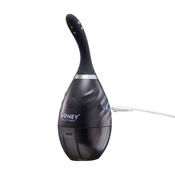 The Bulby Auto Spray Anal Douche System by Honey Play Box is a black, egg-shaped USB-rechargeable device with a curved top that offers effortless, automatic personal hygiene.