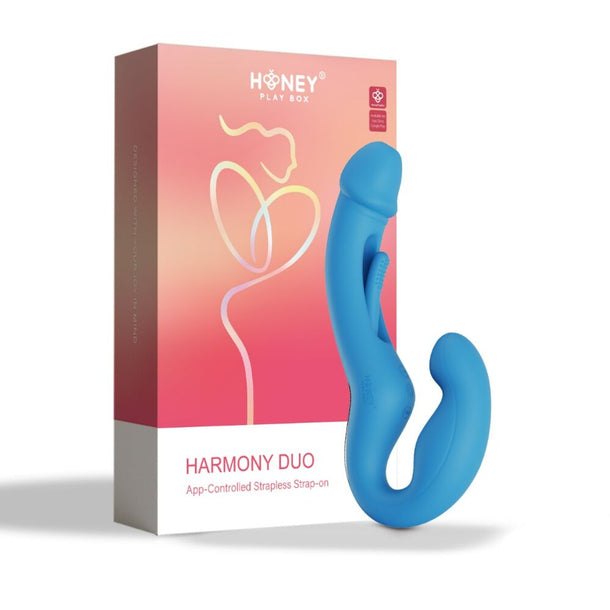 A blue Harmony App-Enabled Strapless Strap On stands upright before its pink and orange box, featuring abstract line art and the Honey Play Box logo—ideal for double-ended play and app-controlled G-spot stimulation.