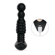 The Pineapple Man Rolling Bead Prostate Vibrator with App Control is a black silicone massager featuring textured surfaces, rolling beads, and a rounded tip. An inset highlights the charging port with a white USB cable plugged in.