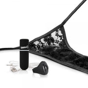 A pair of black lace panties is partially shown lying on a white surface. Next to the My Secret Remote Control One Size Vibrating Panties by Screaming O are a small cylindrical black device with a logo, a black silicone attachment, and a USB charging cable, suggesting this intimate wearable product includes waterproof features and possibly wireless remote control.
