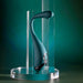 The Pinpoint Perfection Flexible Slim Vibrator, a sleek teal device with a curved design, stands upright on a clear round platform amid vertical acrylic panels, set against a green gradient background.