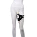 A white mannequin is shown wearing the Sportsheets Pivot Forced Orgasm and Thigh Mount Strap-on Harness in black around the left thigh. Attached to the harness is a white cylindrical device positioned vertically along the inner thigh. The background is plain white.