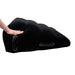 A person lightly pressing on the Pivot Plus Large Inflatable Sex Positioner Wedge Cushion from Sportsheets, demonstrating its flexibility and softness. The black wedge pillow is designed for ergonomic support and features handles on the sides for easy adjustment and positioning.