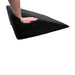 A person's hand pressing onto a black Pivot Positioner Plus Large Sex Wedge Cushion by Sportsheets, demonstrating its firmness and stability with handles on the sides.