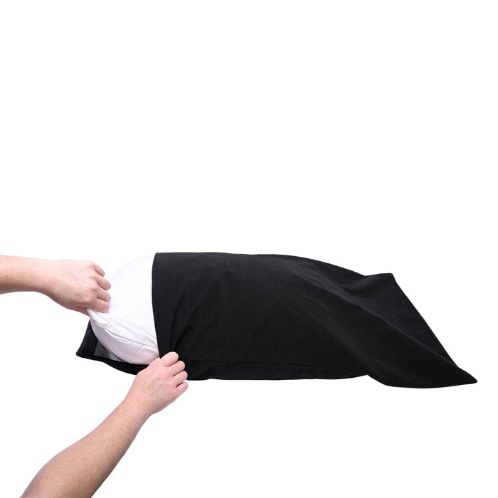 A pair of hands are shown placing or removing a white pillow from a black Pivot Waterproof Pillow Protector by Sportsheets. The pillow protector, which could easily double as a sexy accessory, is partially open, revealing the pillow inside. The background is white.