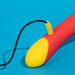 The Romp Hype Rechargeable Silicone G-Spot Vibrator, shown in red and yellow with a rounded end, is being charged with a black cable against a bright blue background.