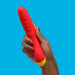 A hand with painted nails holds the Romp Hype Rechargeable Silicone G-Spot Vibrator against a bright blue background.
