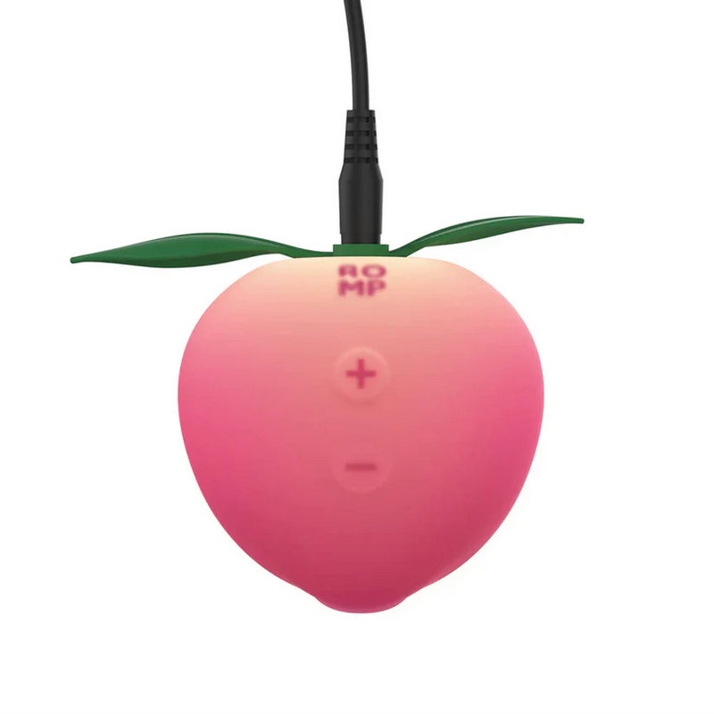Romp Peach Pleasure Air Stimulator, a pink silicone peach with green leaves, charging via a black USB cord.
